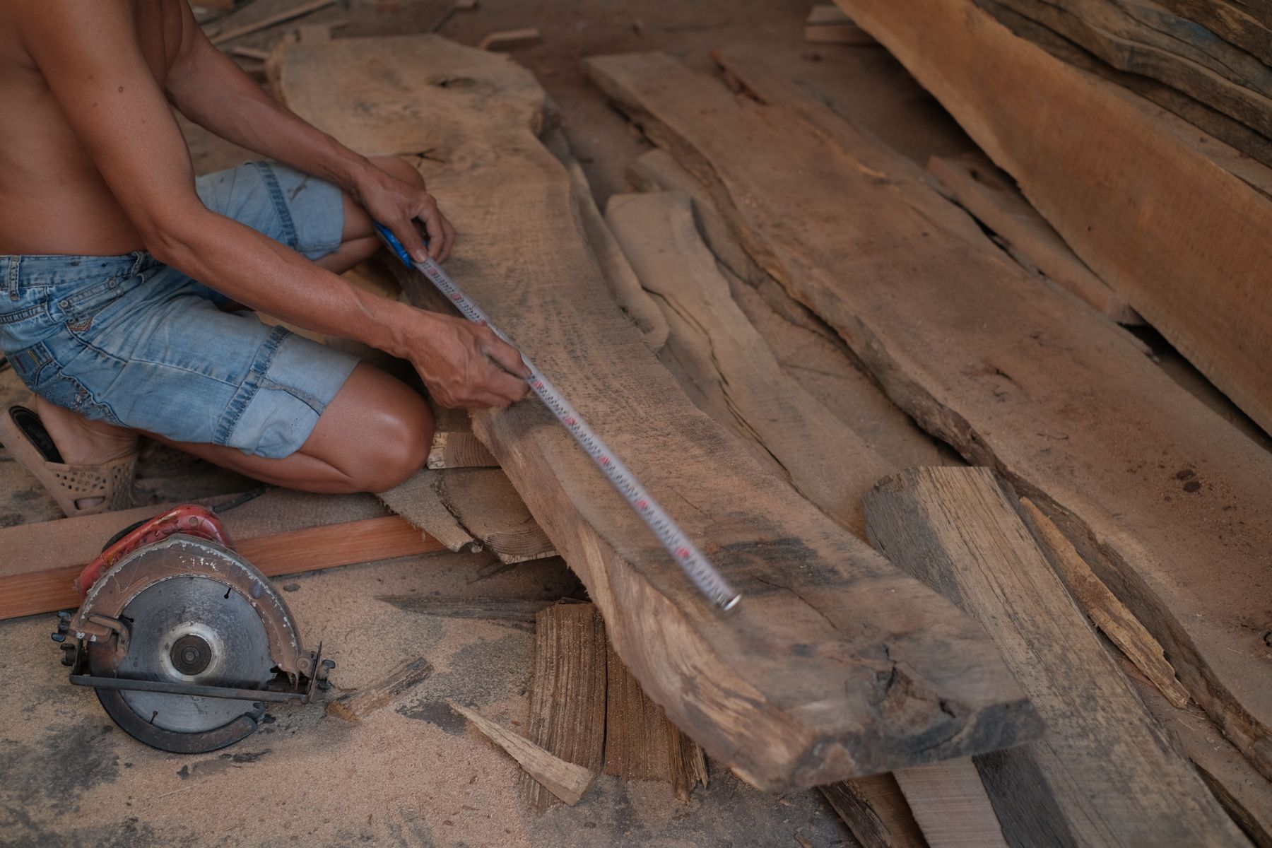 Carpenter measuring a wooden board at a workbench
